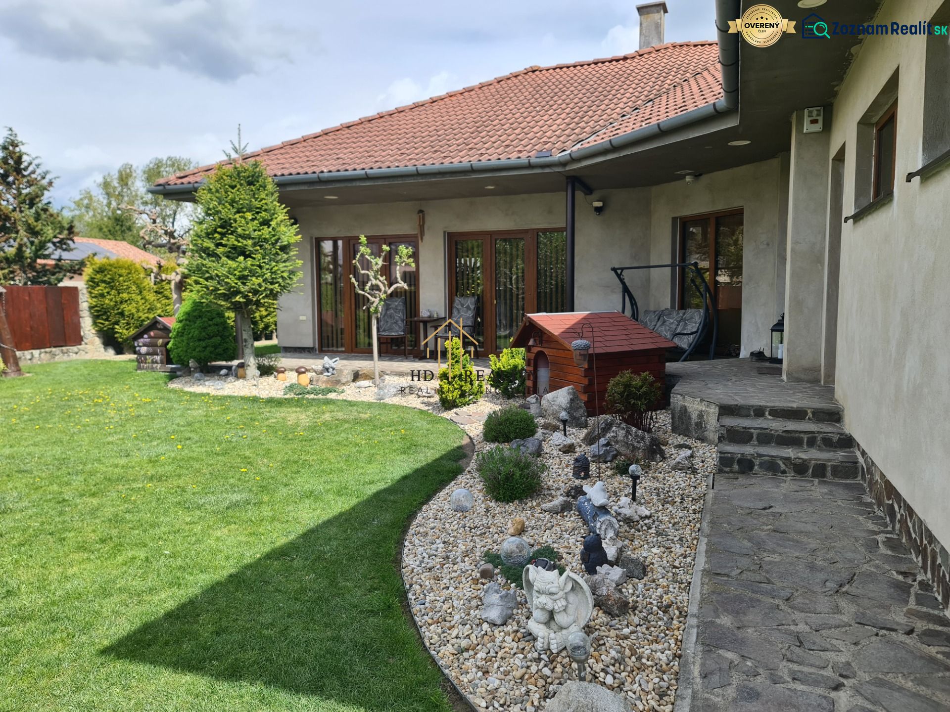 A garden with a well-maintained lawn and a bench in front of a 3-room apartment in Šamorín.