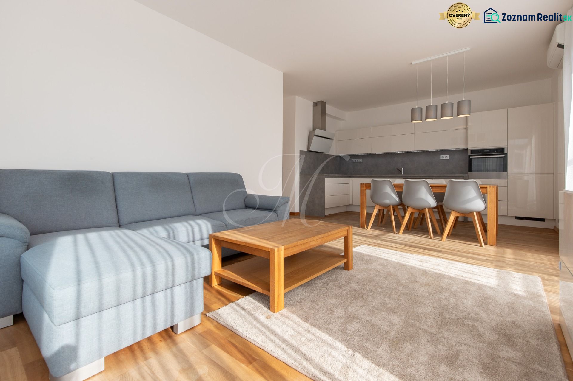 Living room in a 3-room apartment with a wooden decor floor, a sofa, and a kitchenette.