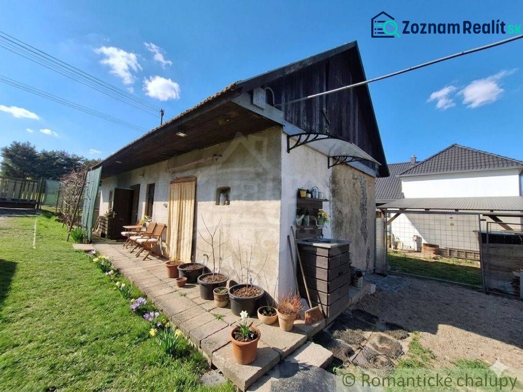A family house in Stožok with a terrace, flower pots, and wooden cladding in the garden.