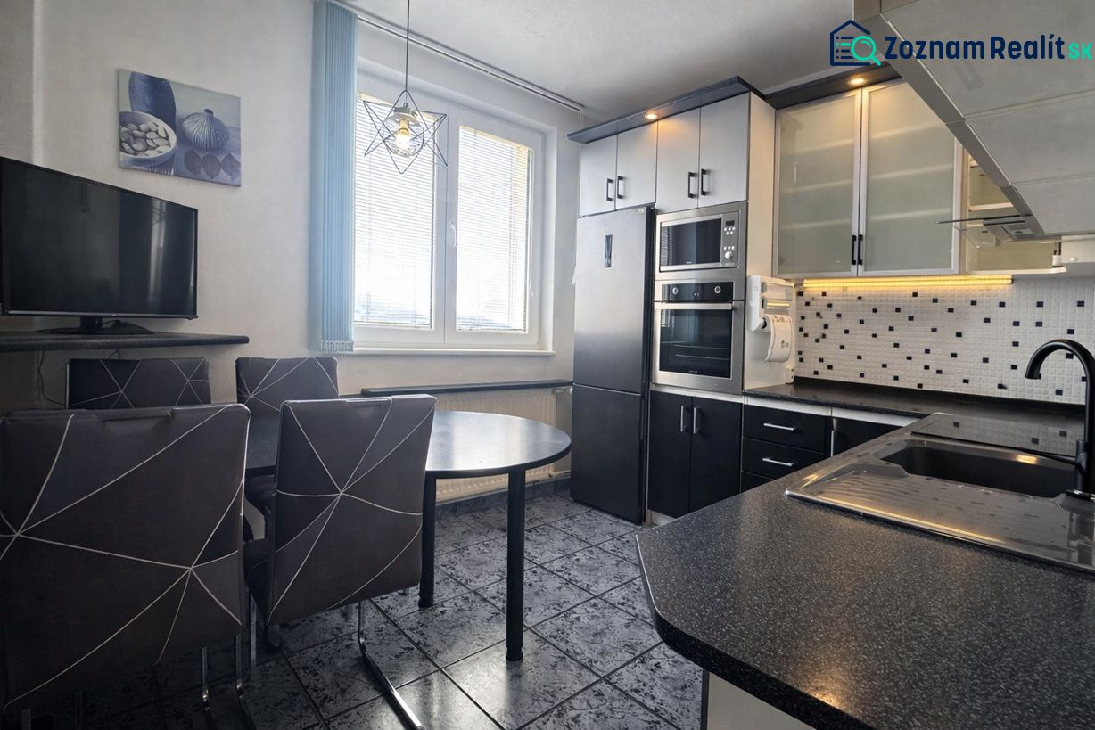 A modern kitchen with dark furniture and built-in appliances in a 3-room apartment.