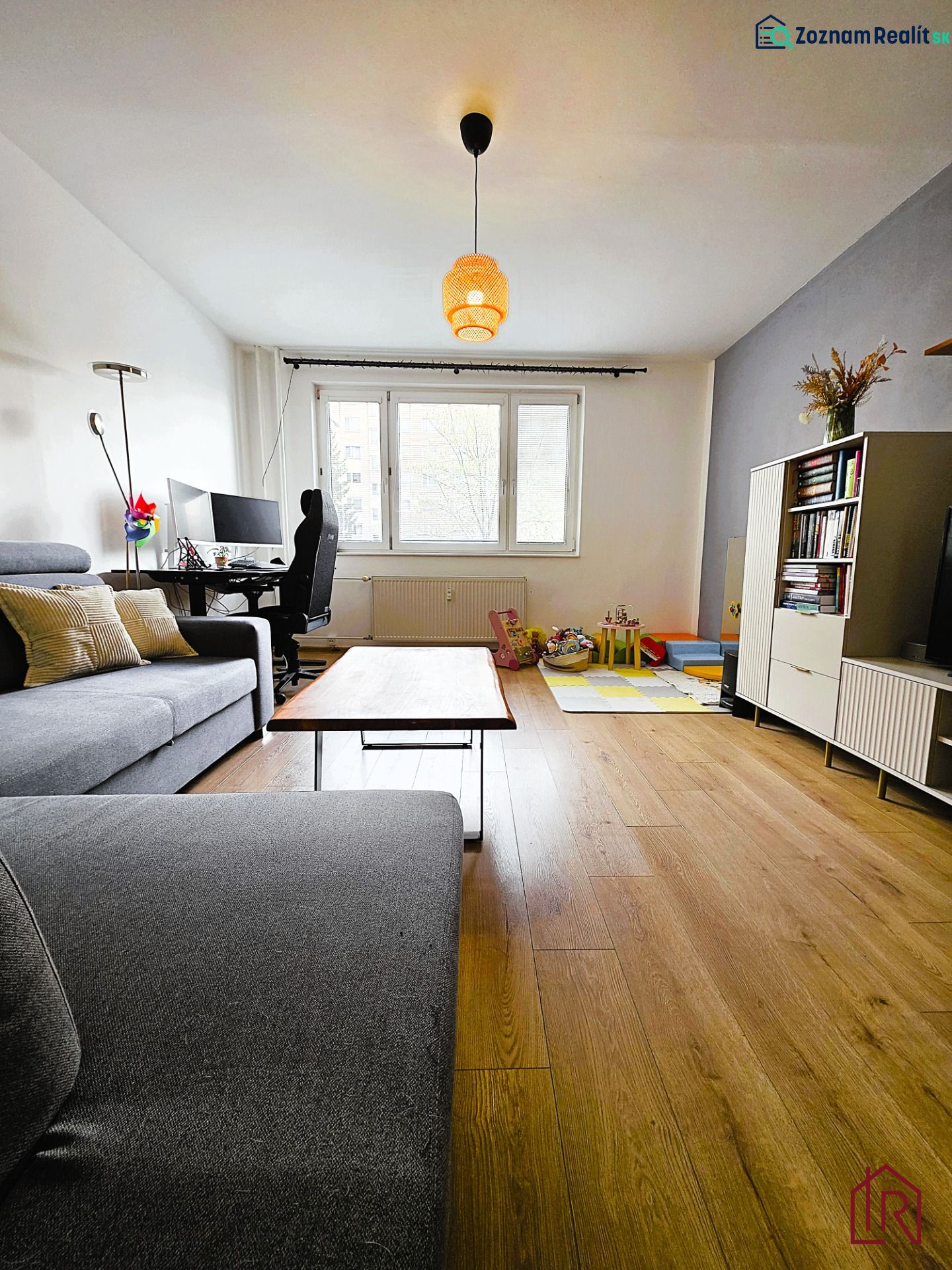 Living room with a gray sofa and a wooden decor floor in a 3-room apartment.