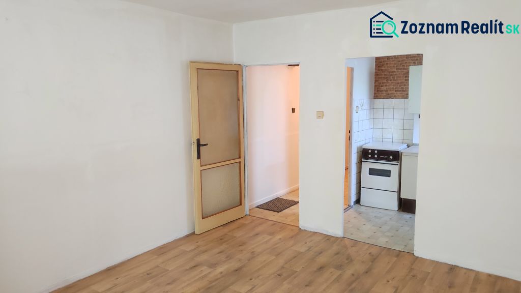 Interior of a 1-room apartment with a wooden decor floor and entrance to the kitchen.
