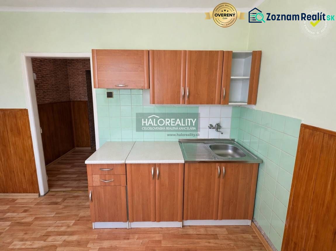 A kitchen in a studio apartment with tiles and wood-patterned flooring.
