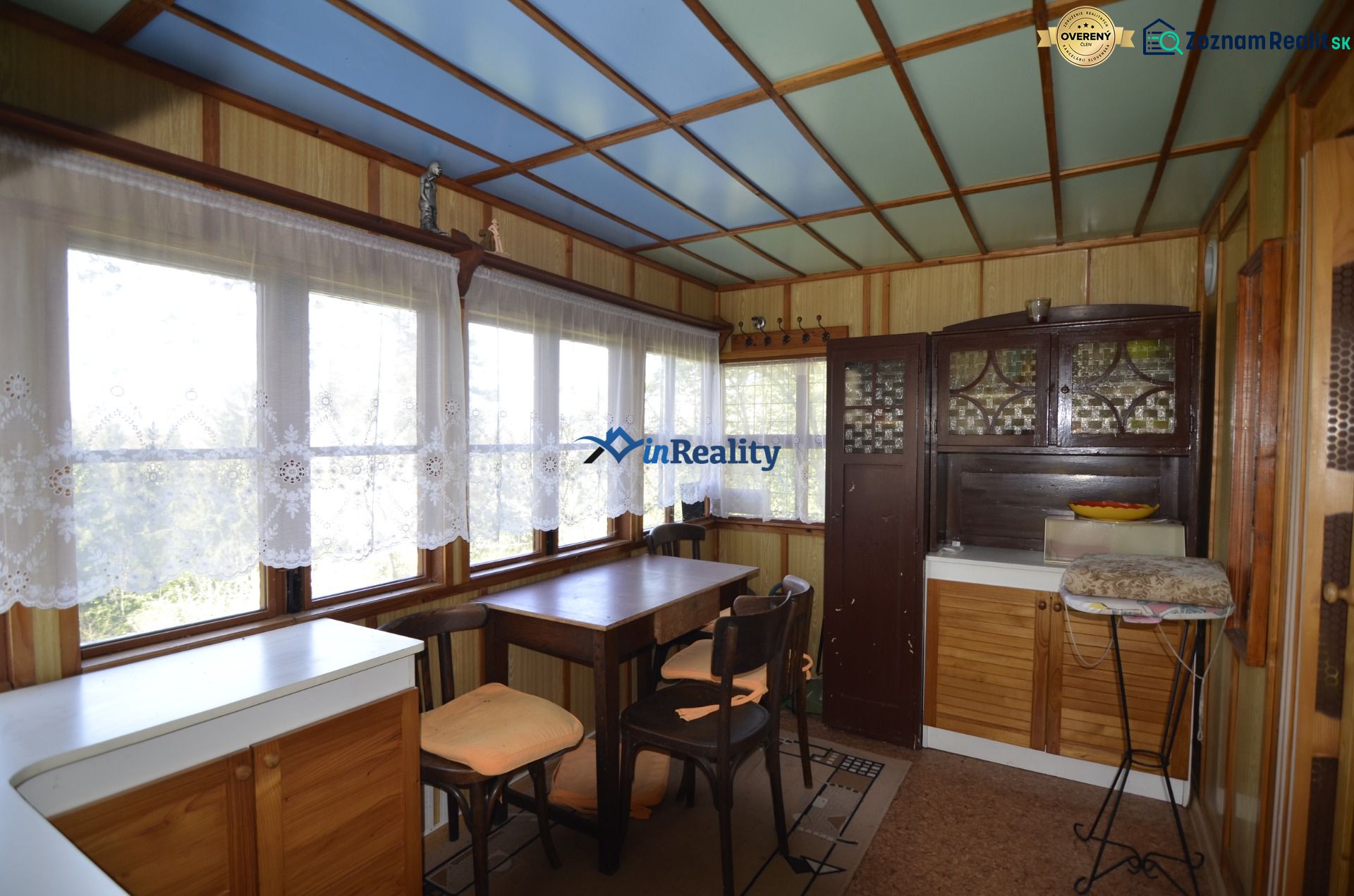 Interior of a garden with a dining table and cabinets, sunny environment through the windows.