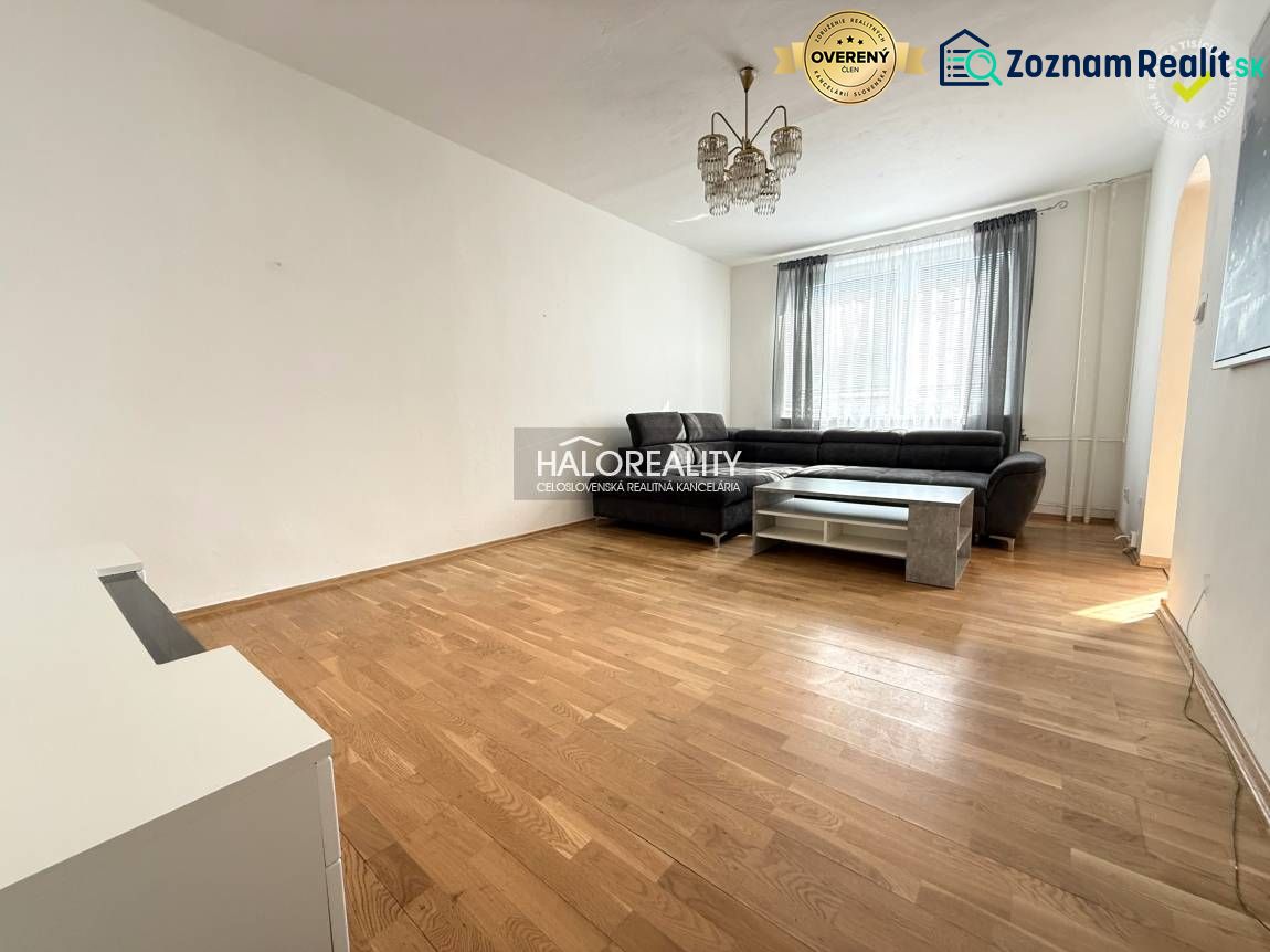 Living room in a three-room apartment with a wooden decor floor and a large sofa.