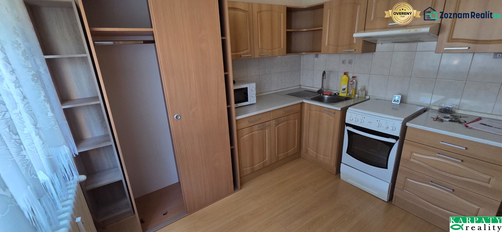 A kitchen in a one-room apartment with a kitchen unit and a floor with a wooden decor.