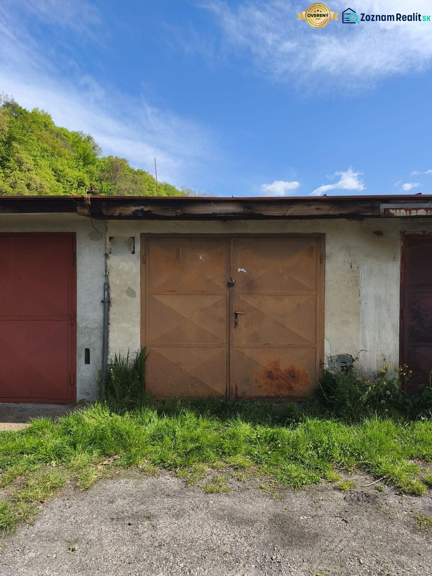 Garages on Dlha Street in Prievidza with a rusty gate and greenery around.