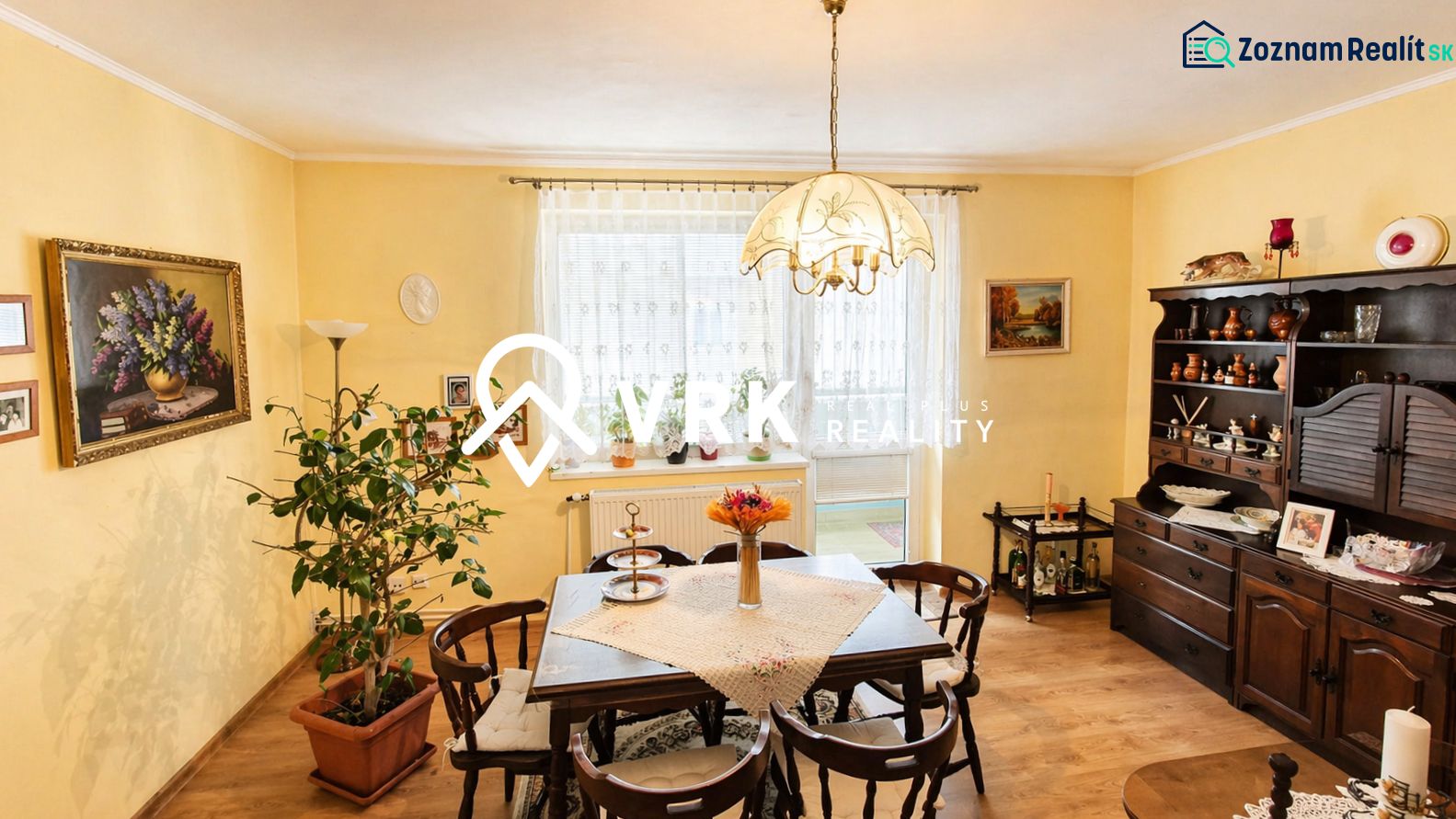 Traditional dining room in a 4-room apartment with wood-patterned flooring and decorations.