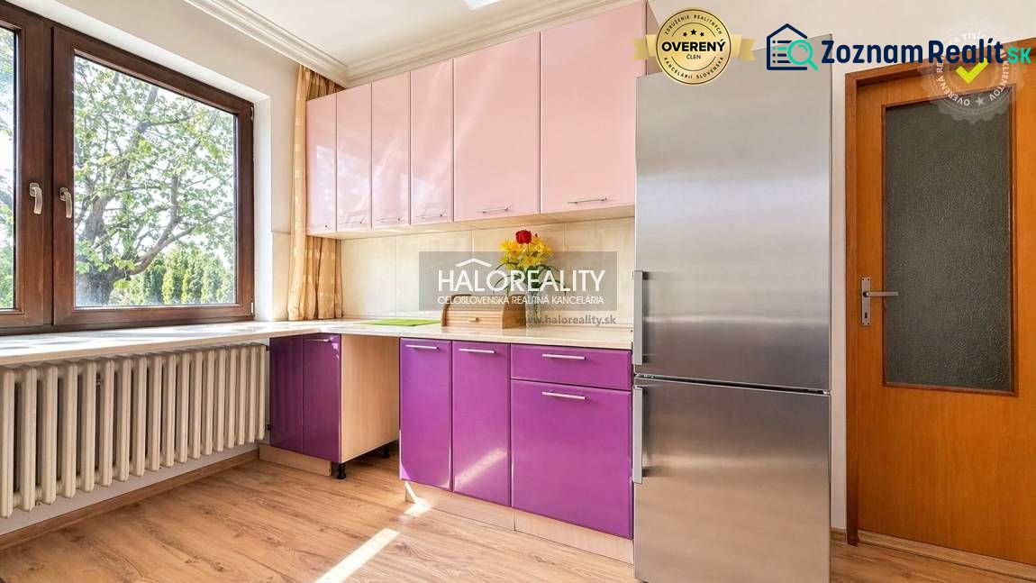 A kitchen in a family house with a colorful cabinet, a stainless steel refrigerator, and a floor with a wooden decor.
