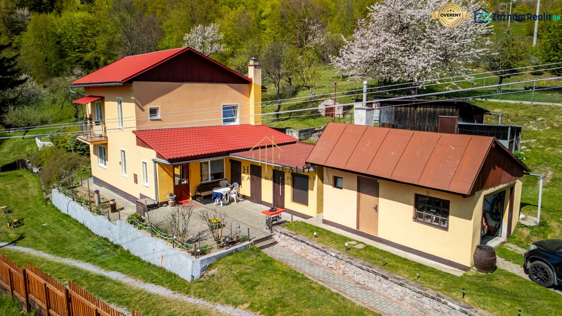 A family house in Štiavnické Bane surrounded by greenery, with a terrace and a red roof.