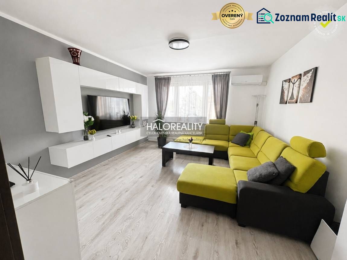 Living room in a three-room apartment with a wooden decor floor and a green sofa.