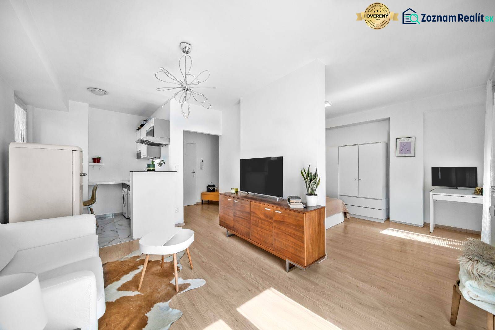 Living room in a 2-room apartment with a TV, the space is bright, flooring with wooden decor.