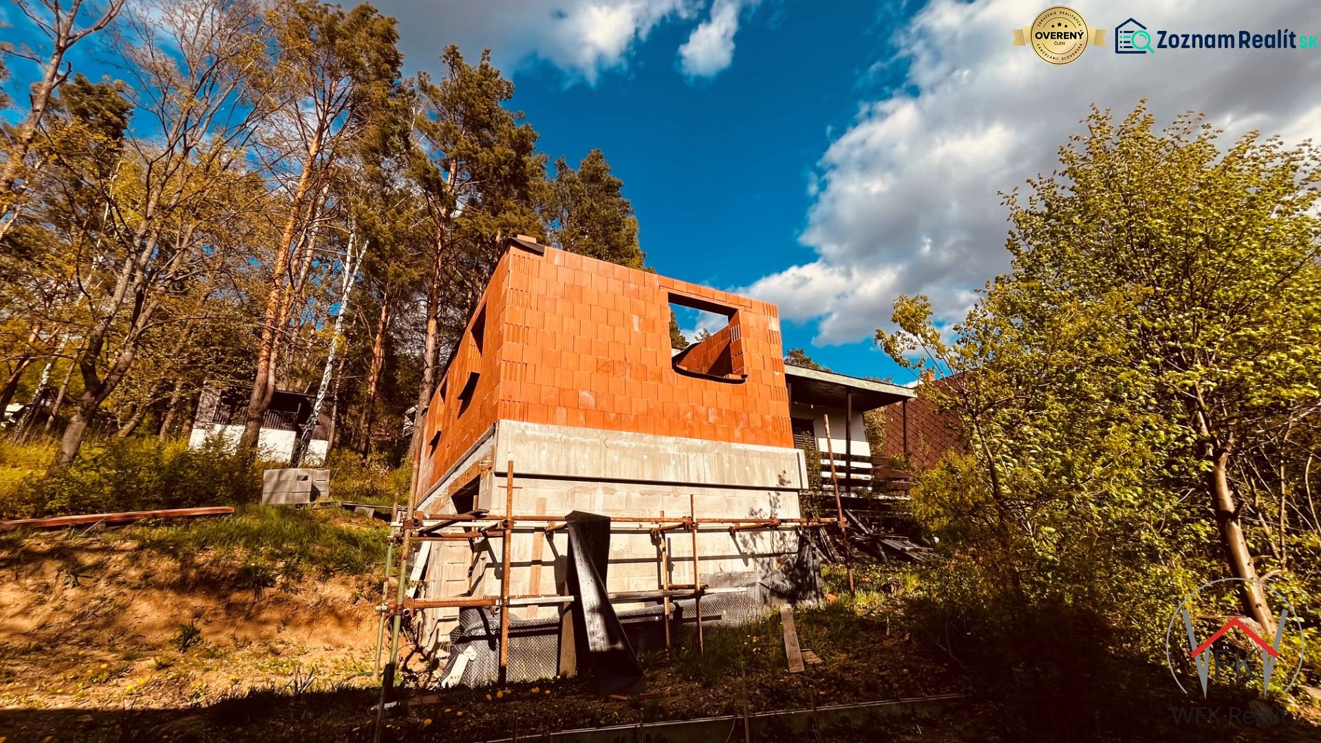A cottage construction in the recreational area of Nová Kelča surrounded by trees and a blue sky.