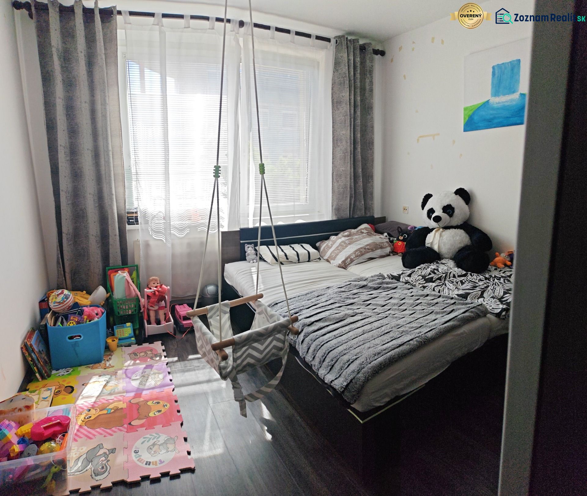 Children's room in a three-room apartment with a wooden decor floor, a hammock, and toys.