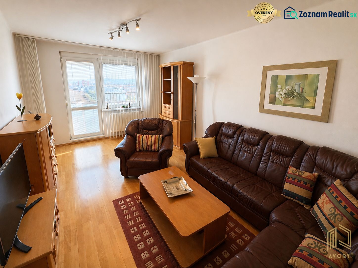 Living room in a three-room apartment with a wooden decor floor and a comfortable couch.