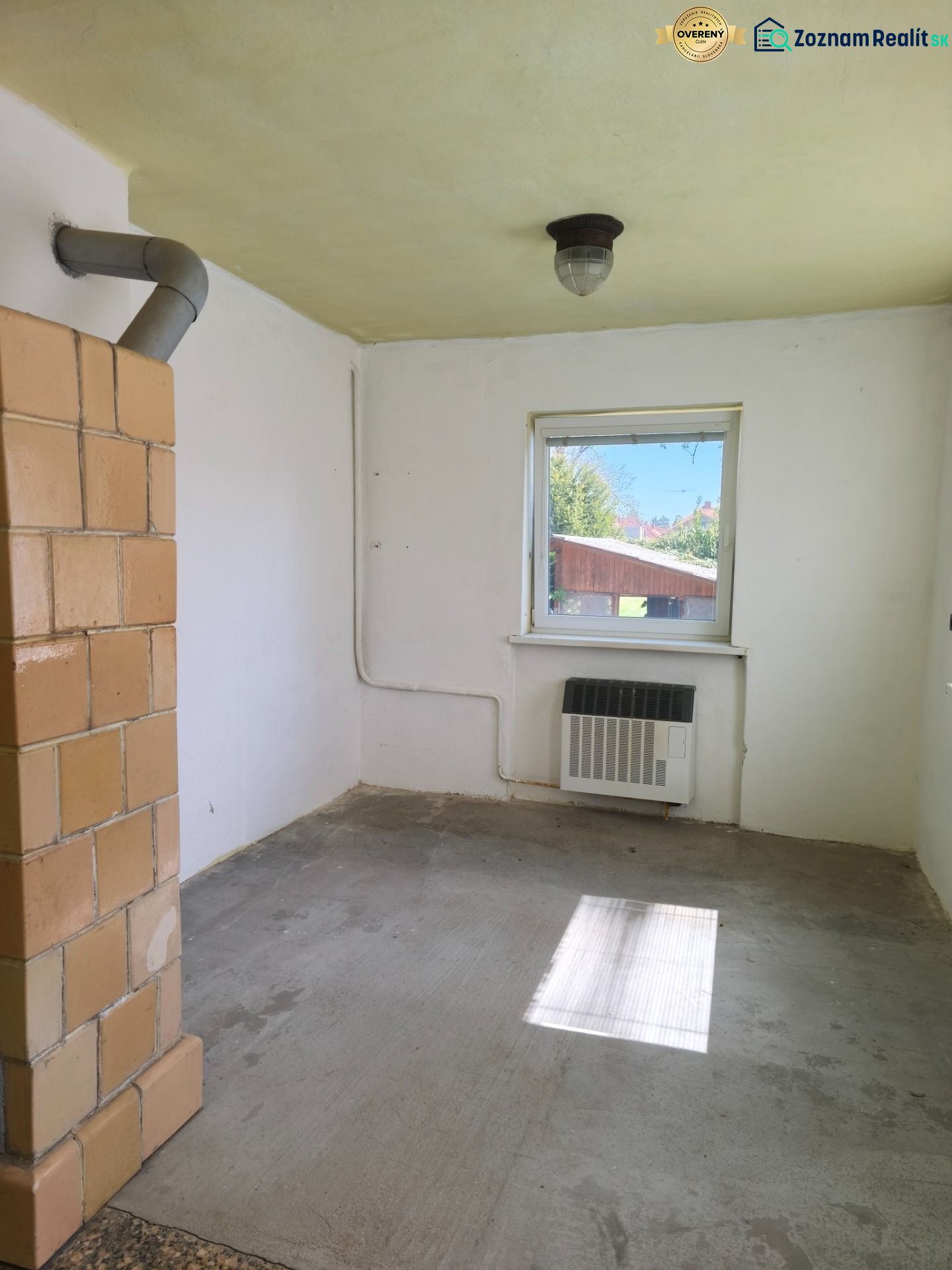 A room in a family house with a stove and a window, without floor decoration.