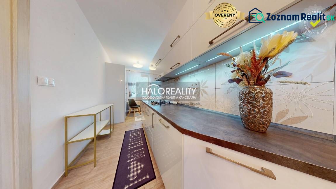 A kitchen unit with decorative tiles, a shelf, and a wooden decor floor in a 2-room apartment.
