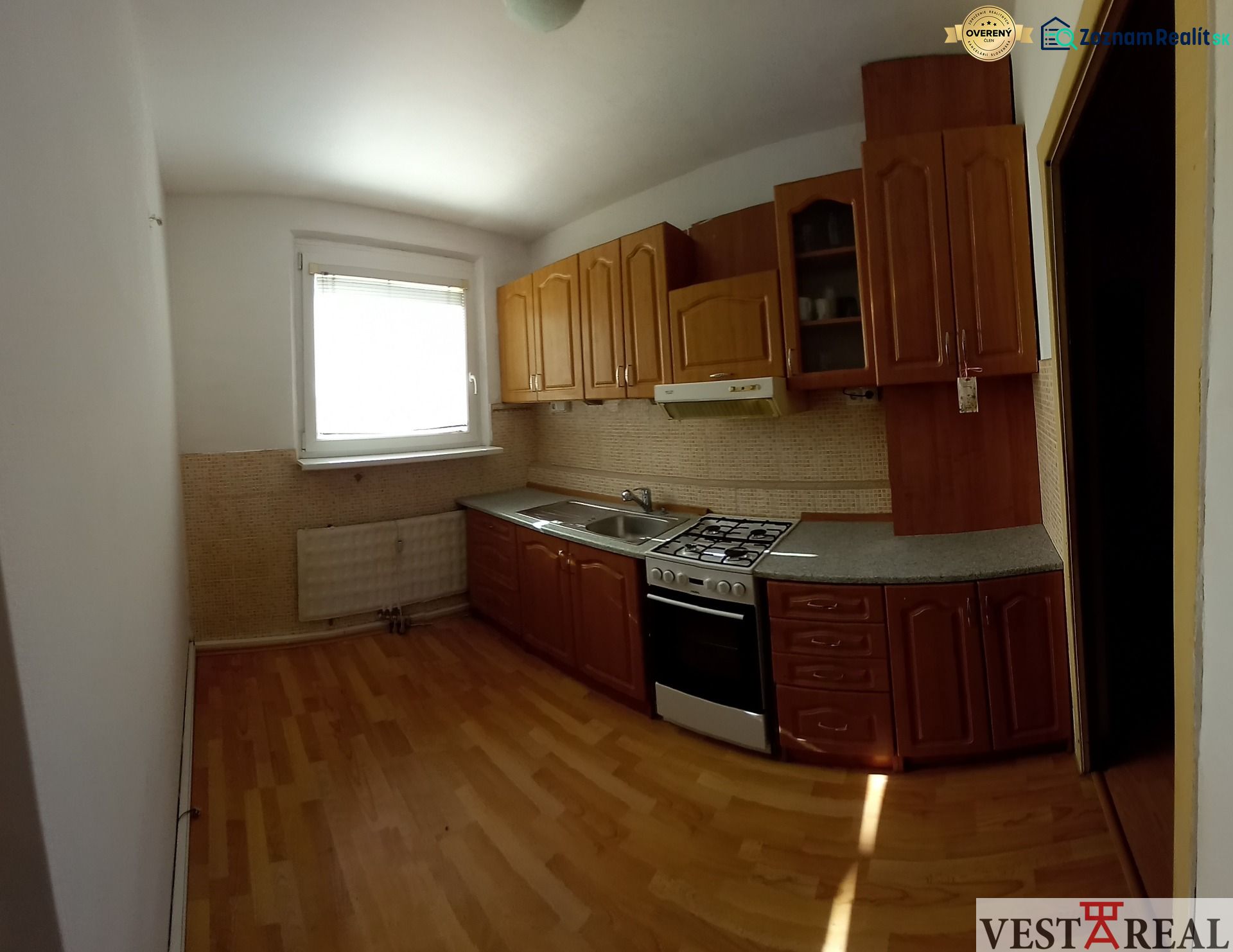 A kitchen in a 3-room apartment with a kitchen unit and a floor with a wooden decor.
