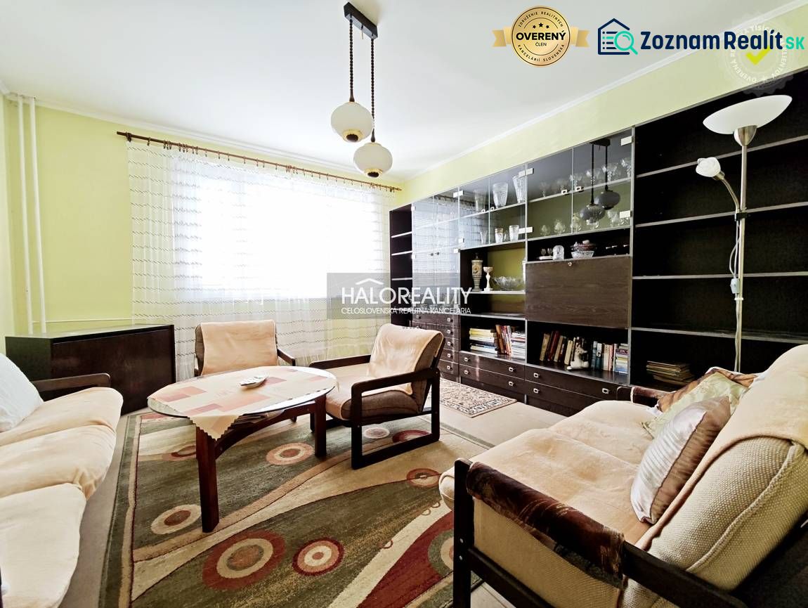 A bright living room in a two-room apartment with wooden furniture and a large bookshelf.
