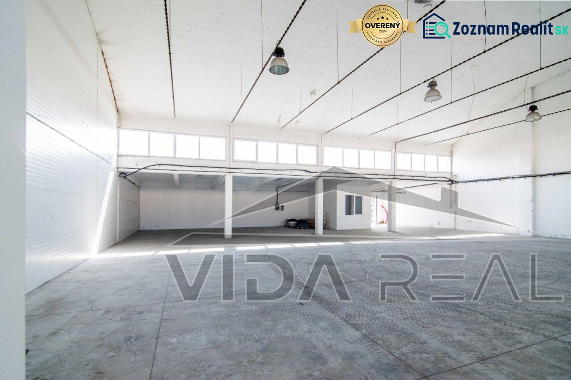 Interior of a warehouse space with a concrete floor and large windows.