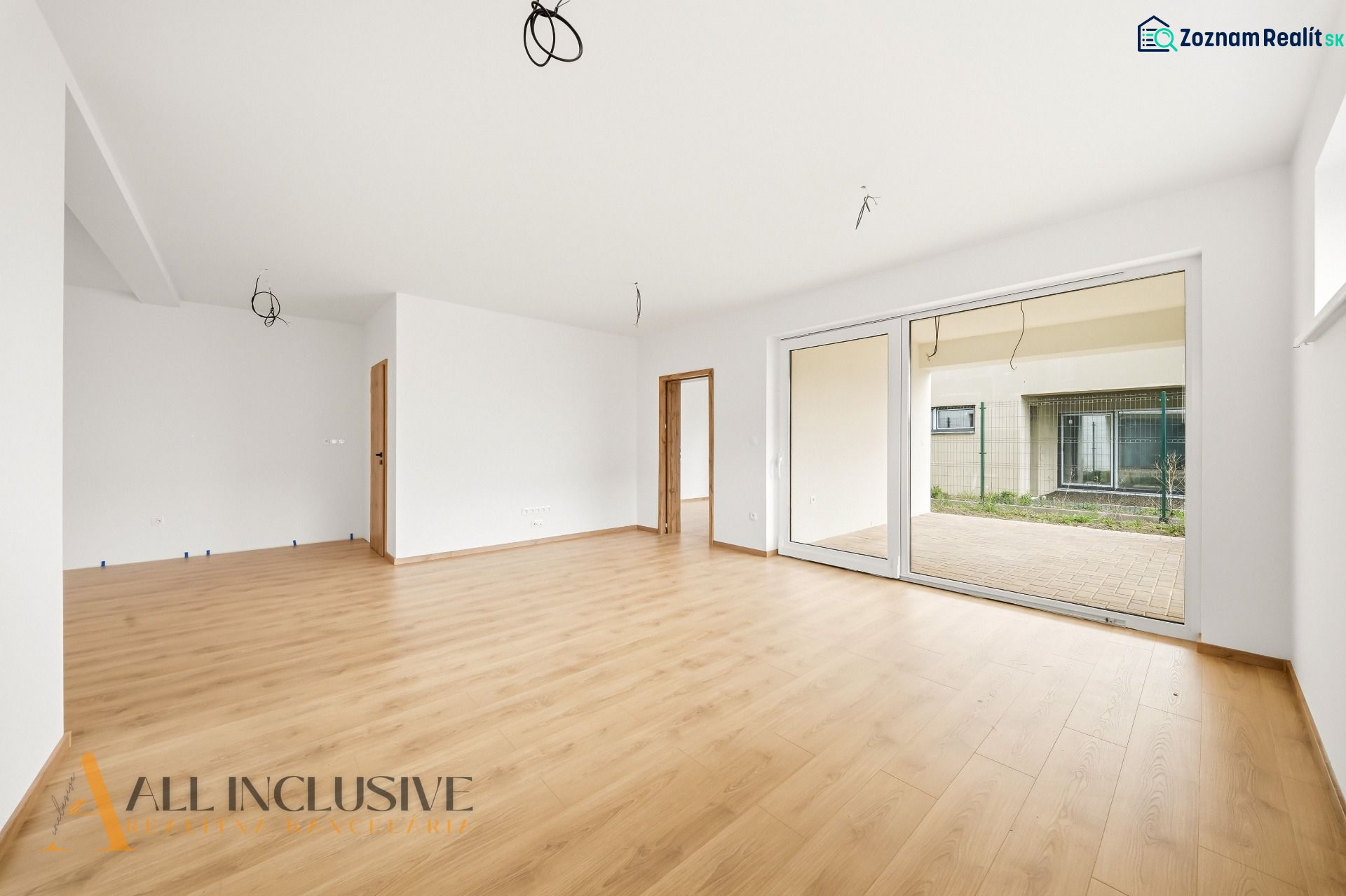 A spacious living room in a family house with a wooden decor floor and large doors to the garden.