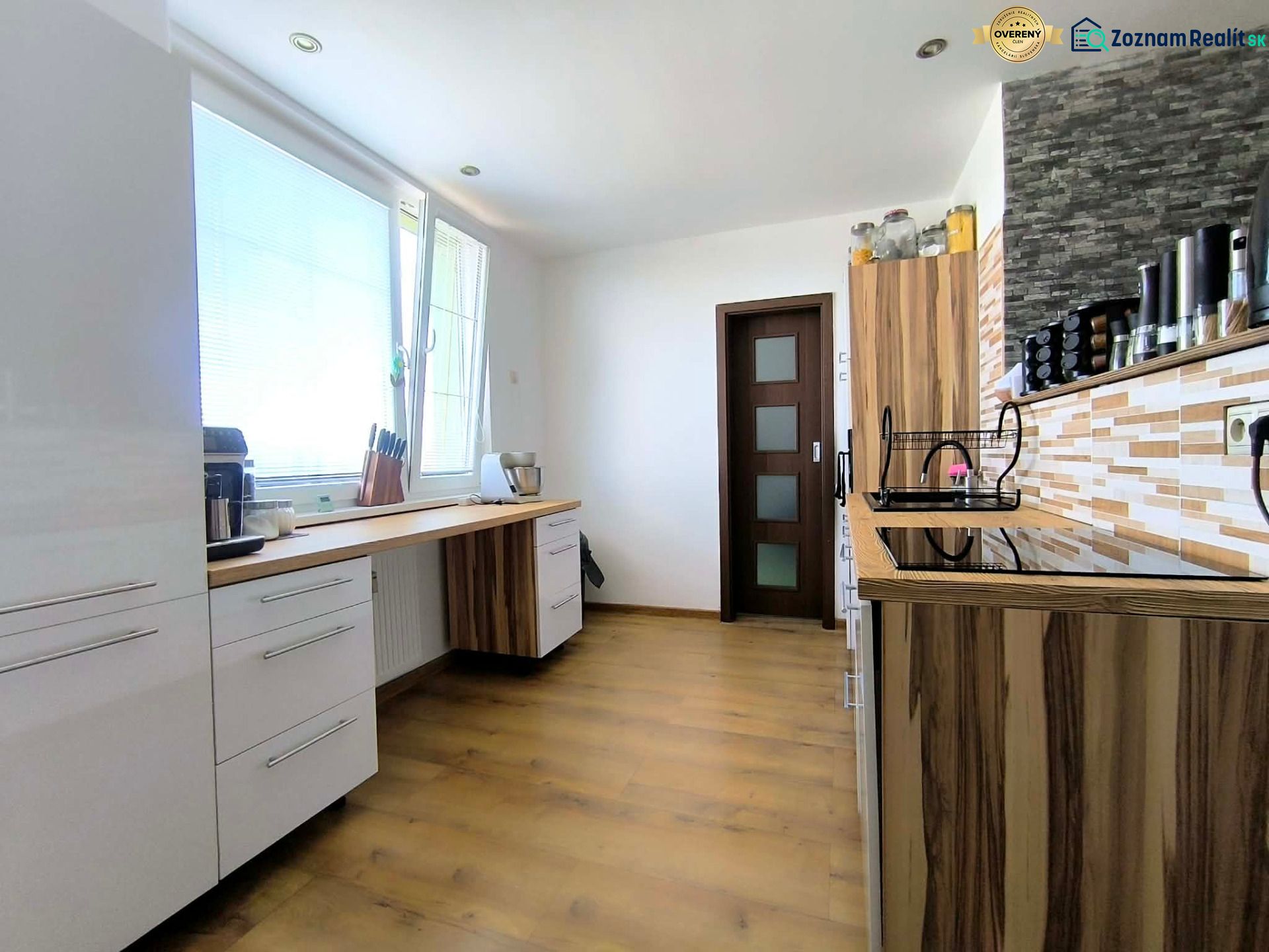 A kitchen in a 3-room apartment with a wooden decor floor, light cabinetry, and practical storage spaces.