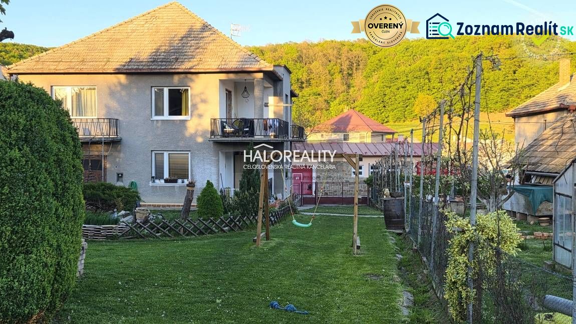 A family house in Poltár with a balcony, garden, and swing, surrounded by greenery.