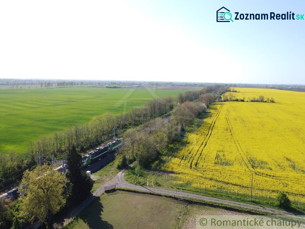 Yellow fields and green meadows near the railway track in Palárikovo. Residential plots.