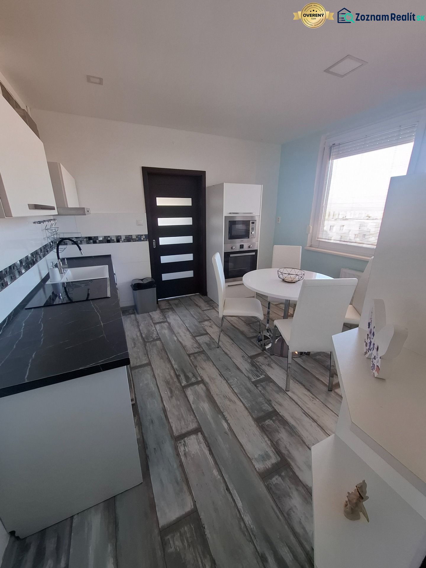A kitchen with a sophisticated black and white unit and a dining table, 3-room apartment.