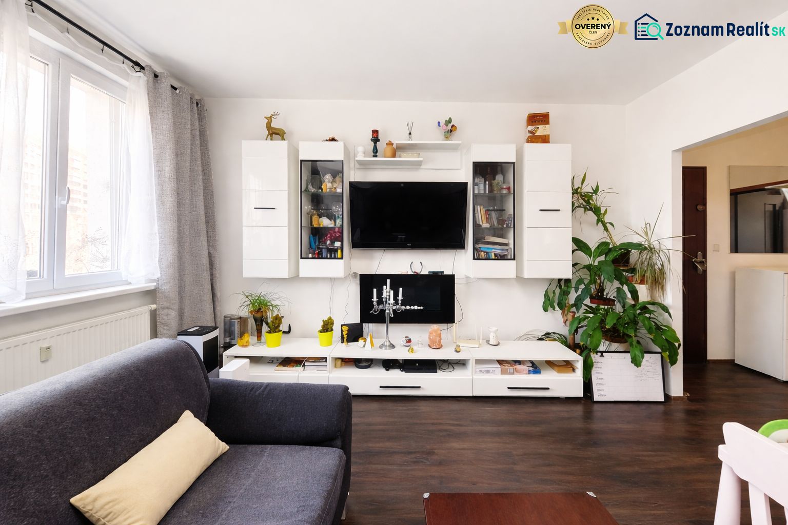Living room in a 4-room apartment with a wooden decor floor and a white living room wall unit.