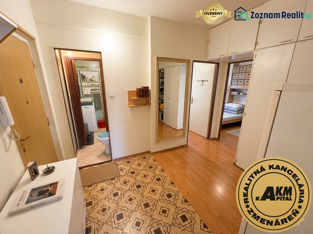 The hallway in a 3-room apartment with a wooden decor floor and entrance to the bathroom.