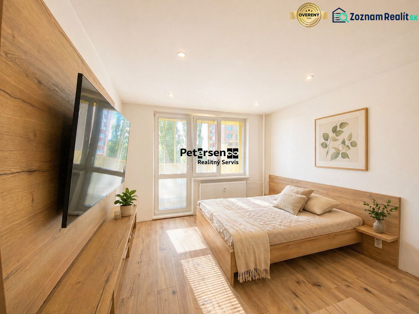 Bedroom in a 2-room apartment with a bed, television, and wooden decor flooring.