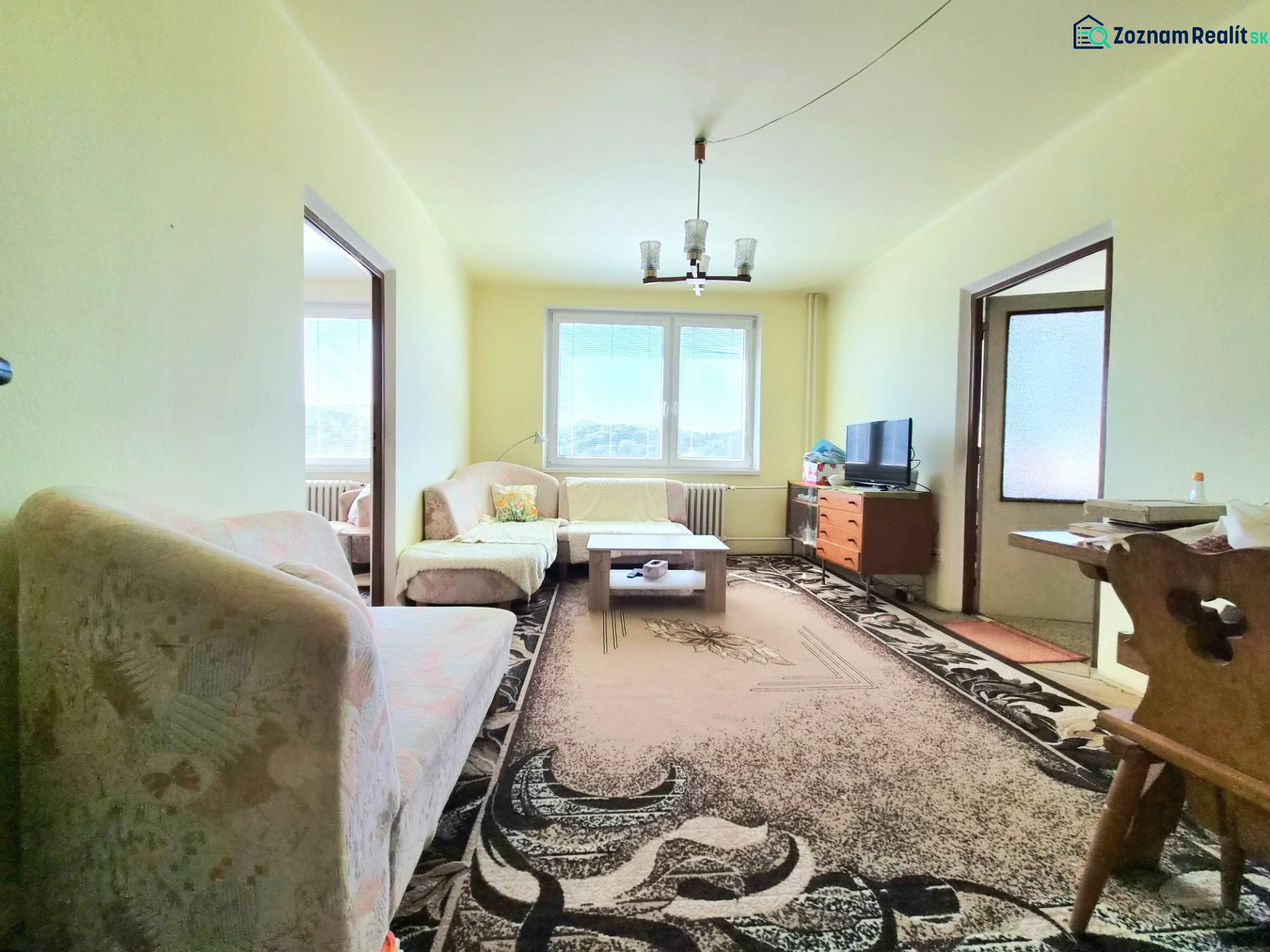 Living room in a 3-room apartment with sofas and carpets on a floor with a wooden decor.