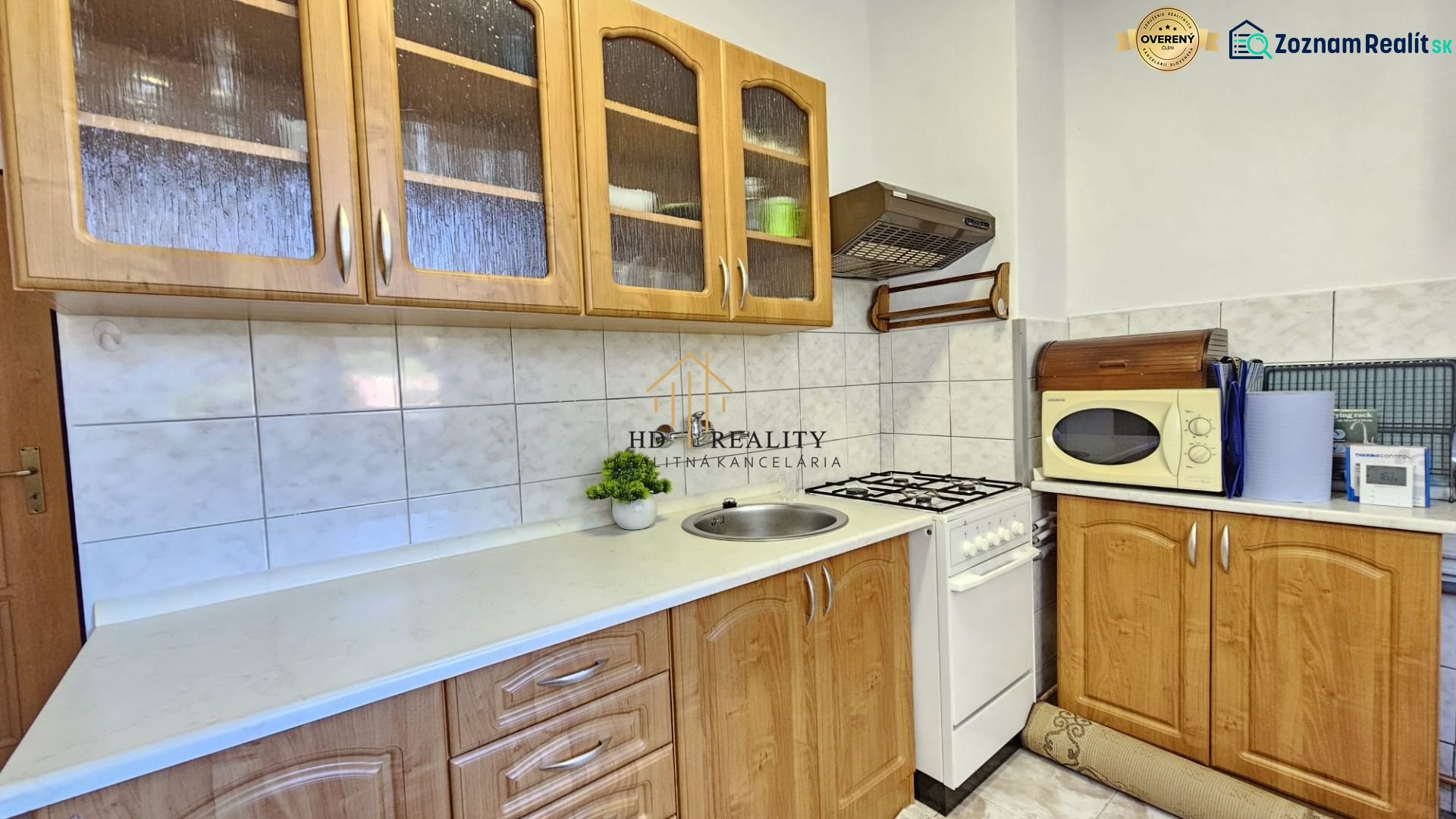 A kitchen in a 2-room apartment with wooden cabinets and a white countertop.