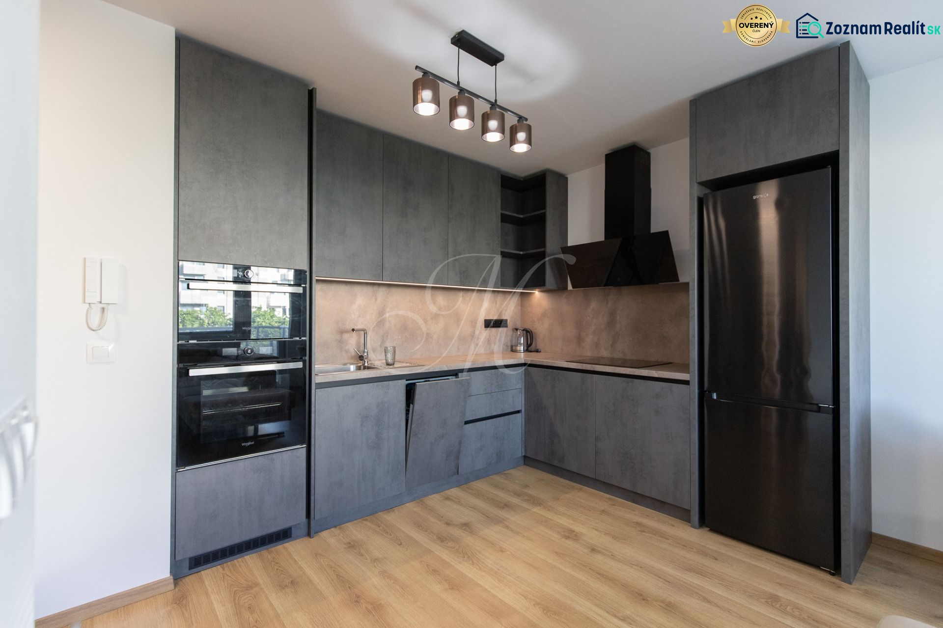 The kitchen in a 2-room apartment with anthracite cabinets and a wooden decor floor.