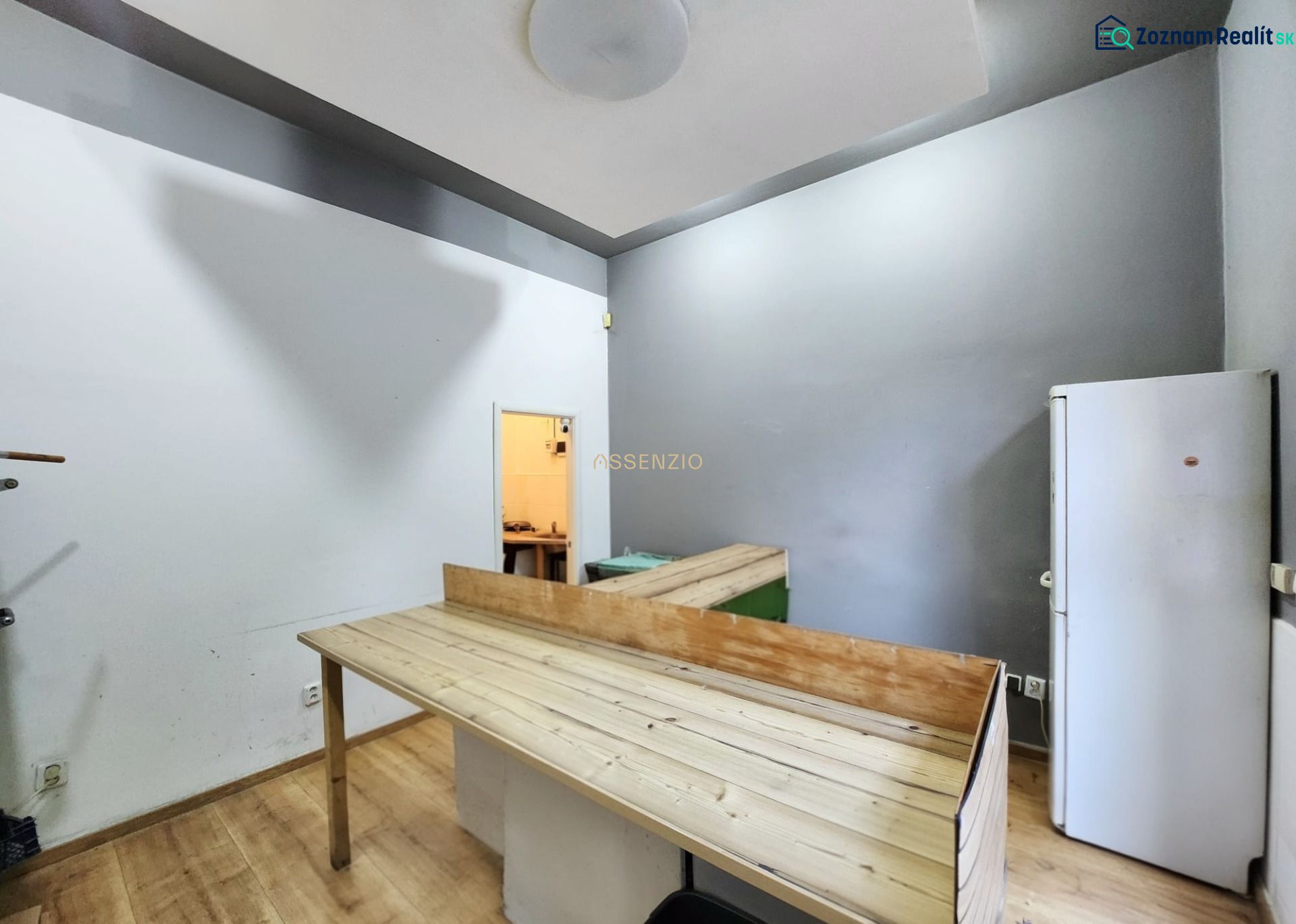 Interior of a gastro space with a wooden decor floor, table, and refrigerator.
