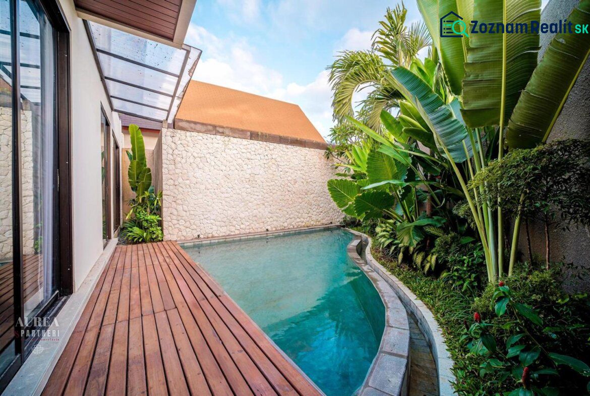 A villa in Bali with a pool surrounded by greenery and a floor with a wooden decor.
