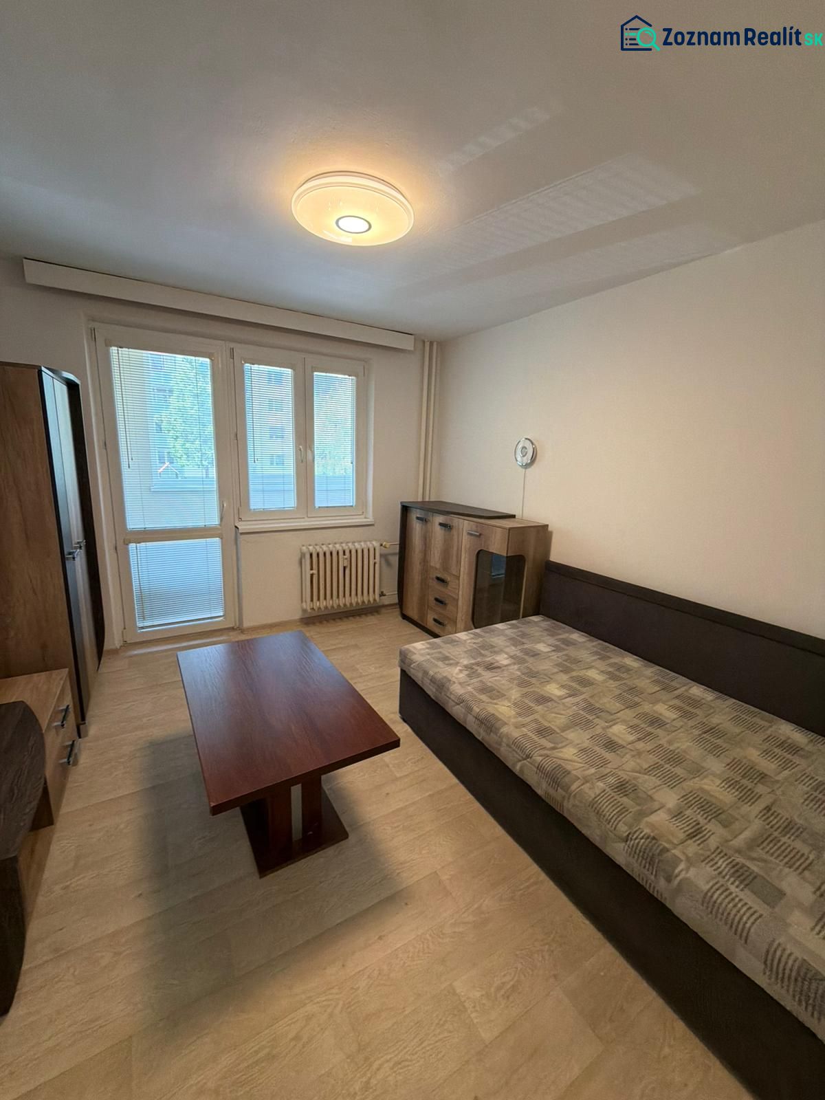 Studio apartment with a bed, coffee table, wardrobe, and floor with a wooden decor.