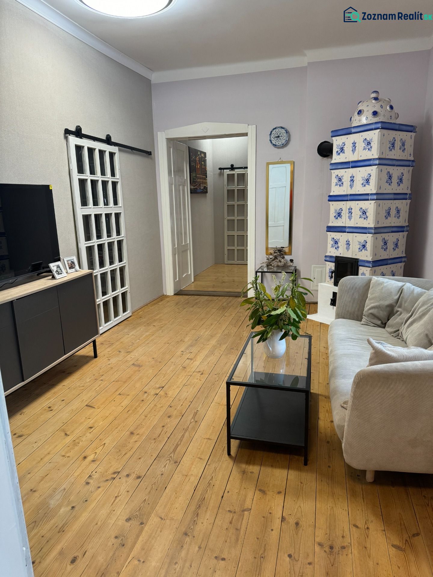 Living room in a family house with a stove and a wooden-patterned floor.