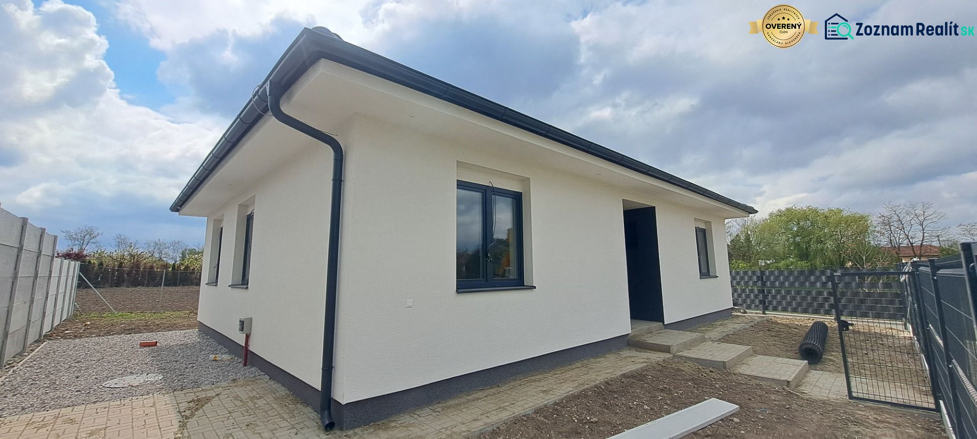 A family house in Selice with a white facade and black roofing elements.
