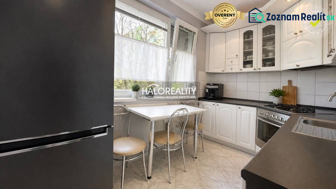 A kitchen in a 3-room apartment with white cabinets, a table, and four chairs.
