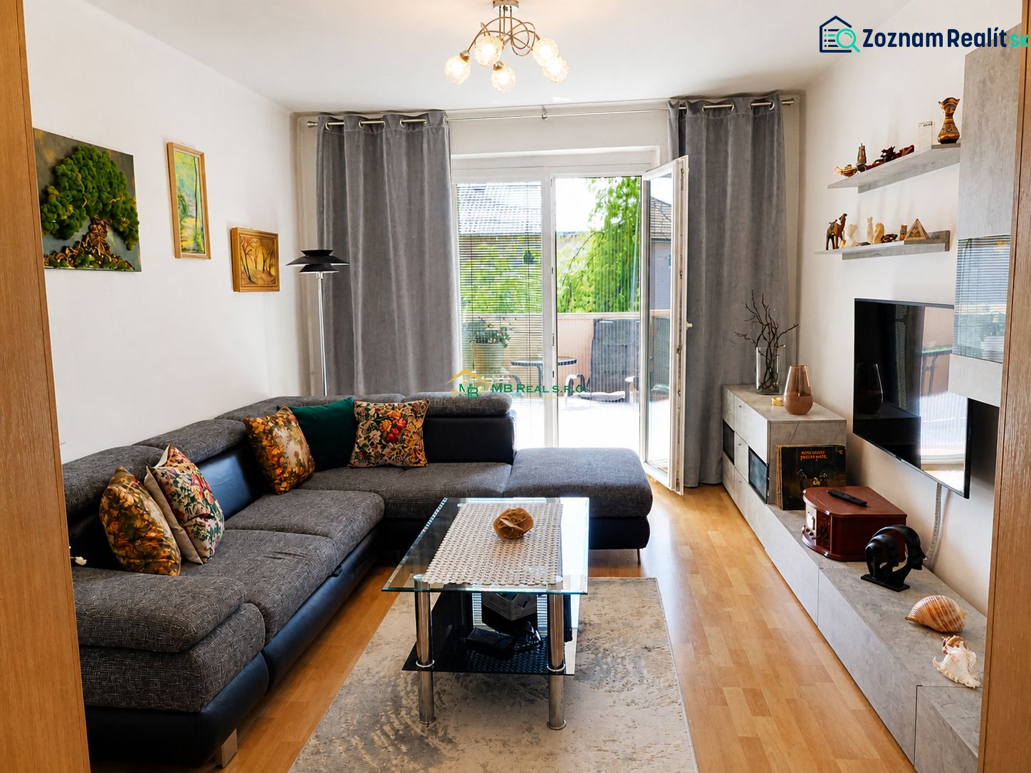 Living room in a two-room apartment with a wooden decor floor and a large sofa.