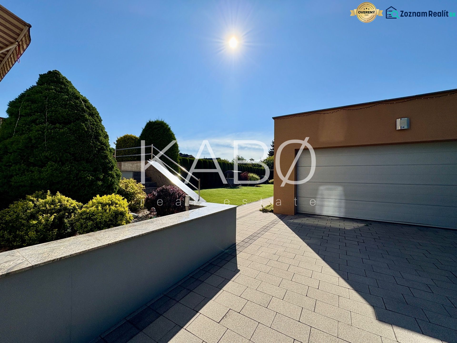 The exterior of a family house in Partizánske with a garden and a garage under sunny weather.