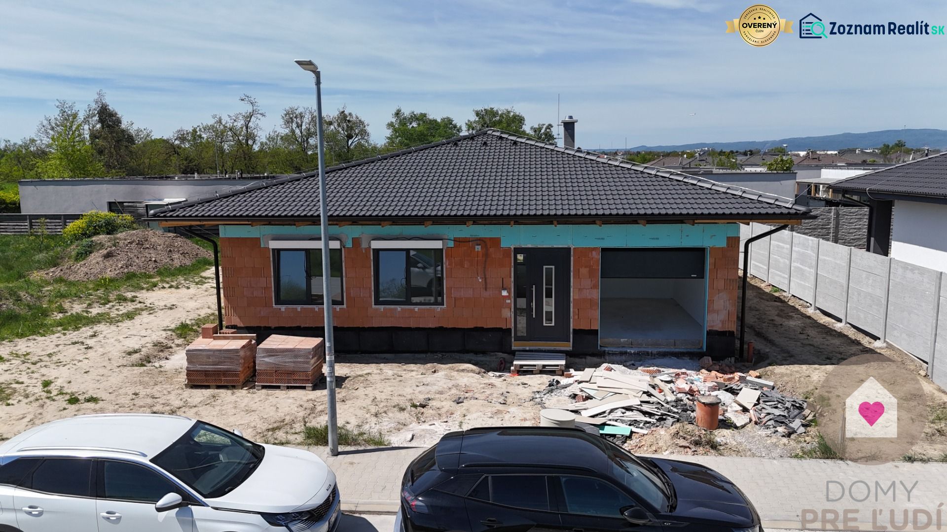 A family house under construction in Bernolákovo, with exposed brickwork and a gray roof.