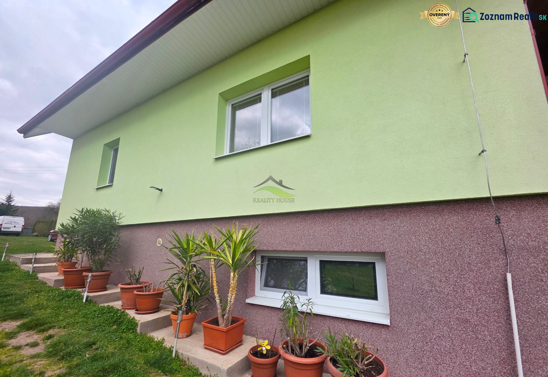 The facade of a family house in Klokočov with flower pots and landscaped greenery in the yard.