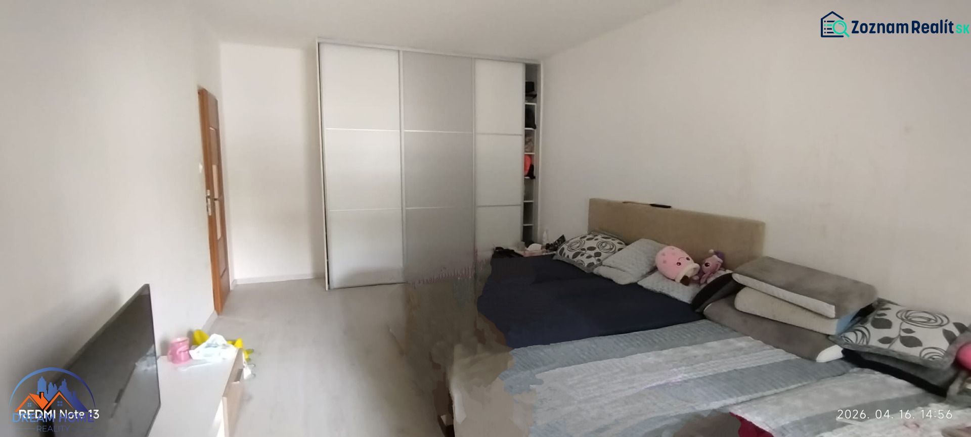 Bedroom in a 2-room apartment with a sliding wardrobe and a bed, floor with wooden decor.
