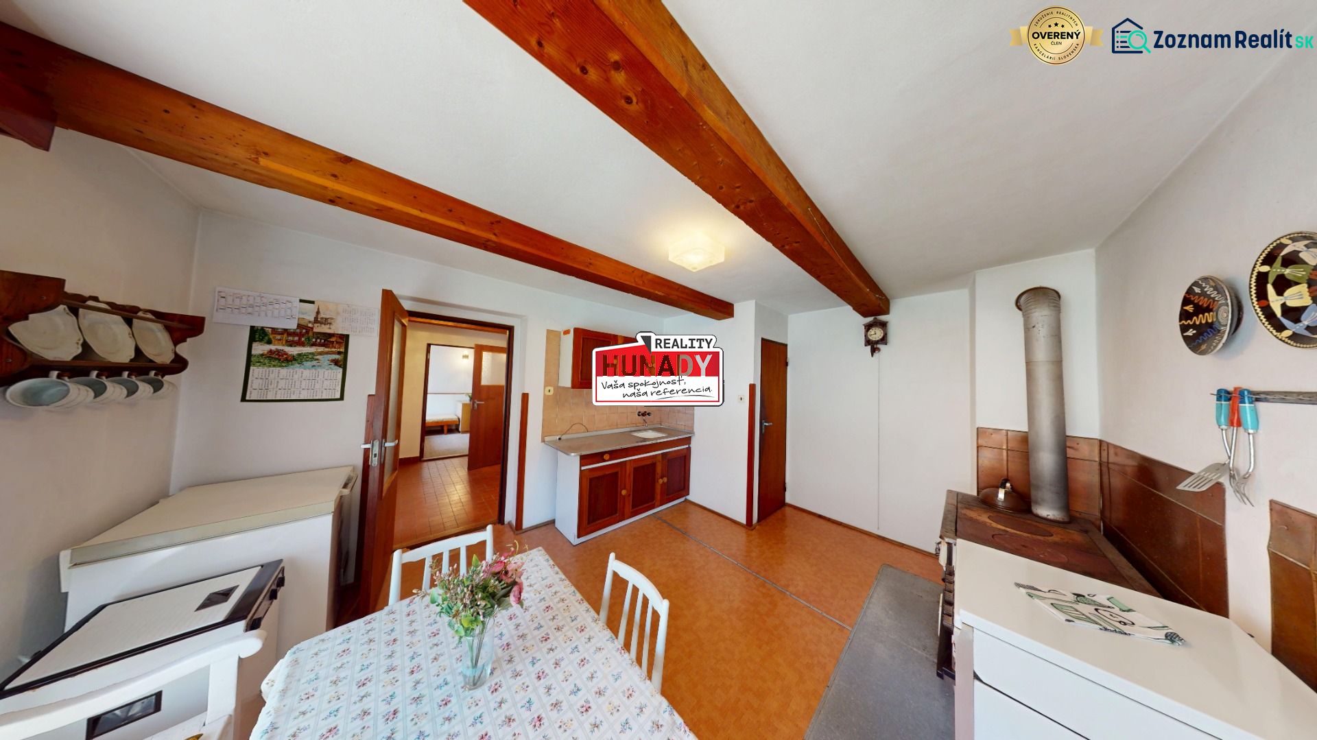 Dining room in a family house with a kitchen, wooden beams, and a traditional stove.