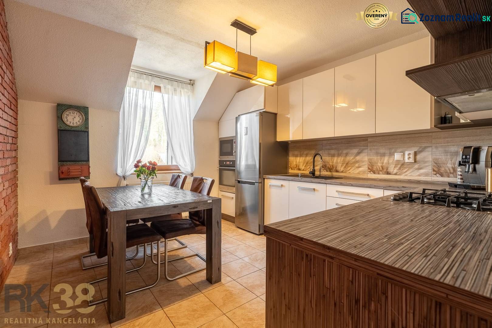 A kitchen in a 4-room apartment with a dining table, chandelier, and modern appliances.