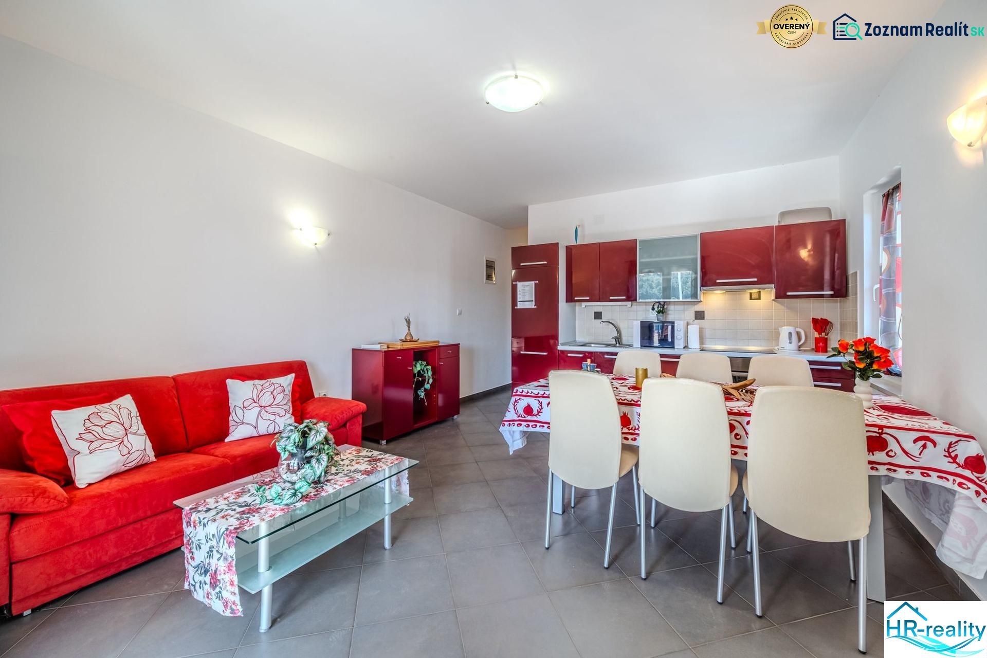 Recreational apartment with a red sofa and a kitchen with a dining area.