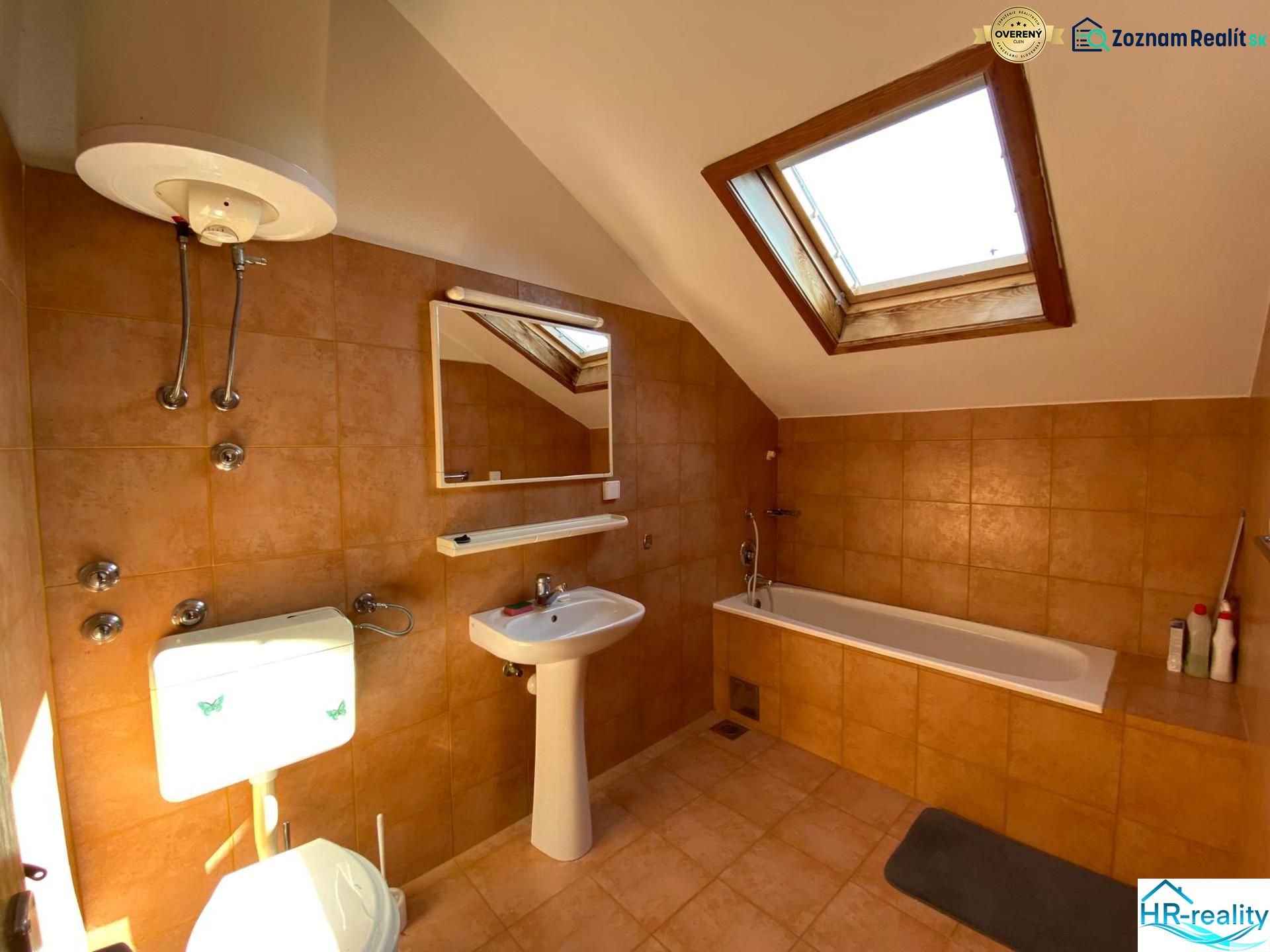 A bathroom in a holiday apartment with a bathtub and a skylight.